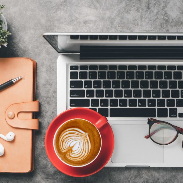 Schreibtisch mit Laptop, Notizbuch, Brille und Kaffeetasse Schreibtisch mit Laptop, Notizbuch, Brille und Kaffeetasse