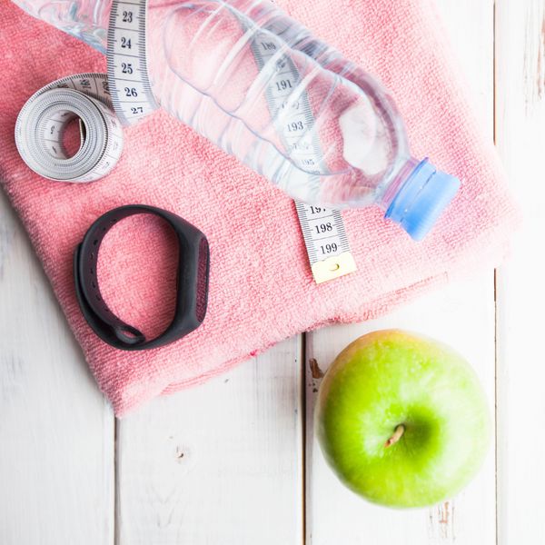 Grüner Apfel, Pinkes Handtuch, Wasserflasche und Fitnessuhr