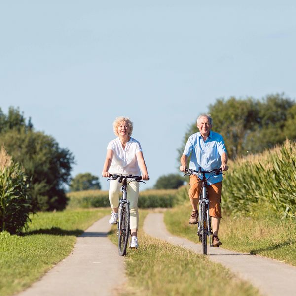 Zwei ältere Personen fahren Fahrrad in der Natur