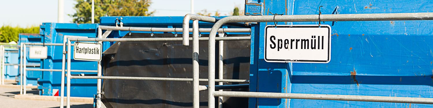 Drei blaue Container auf dem Wertstoffhof mit den Schildern "Sperrmüll", "Hartplastik" und "Holz" Drei blaue Container auf dem Wertstoffhof mit den Schildern "Sperrmüll", "Hartplastik" und "Holz"