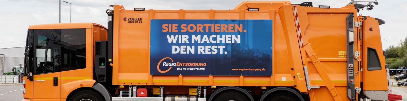 Pressmüllfahrzeug der RegioEntsorgung mit Banner "Sie sortieren. Wir machen den Rest"